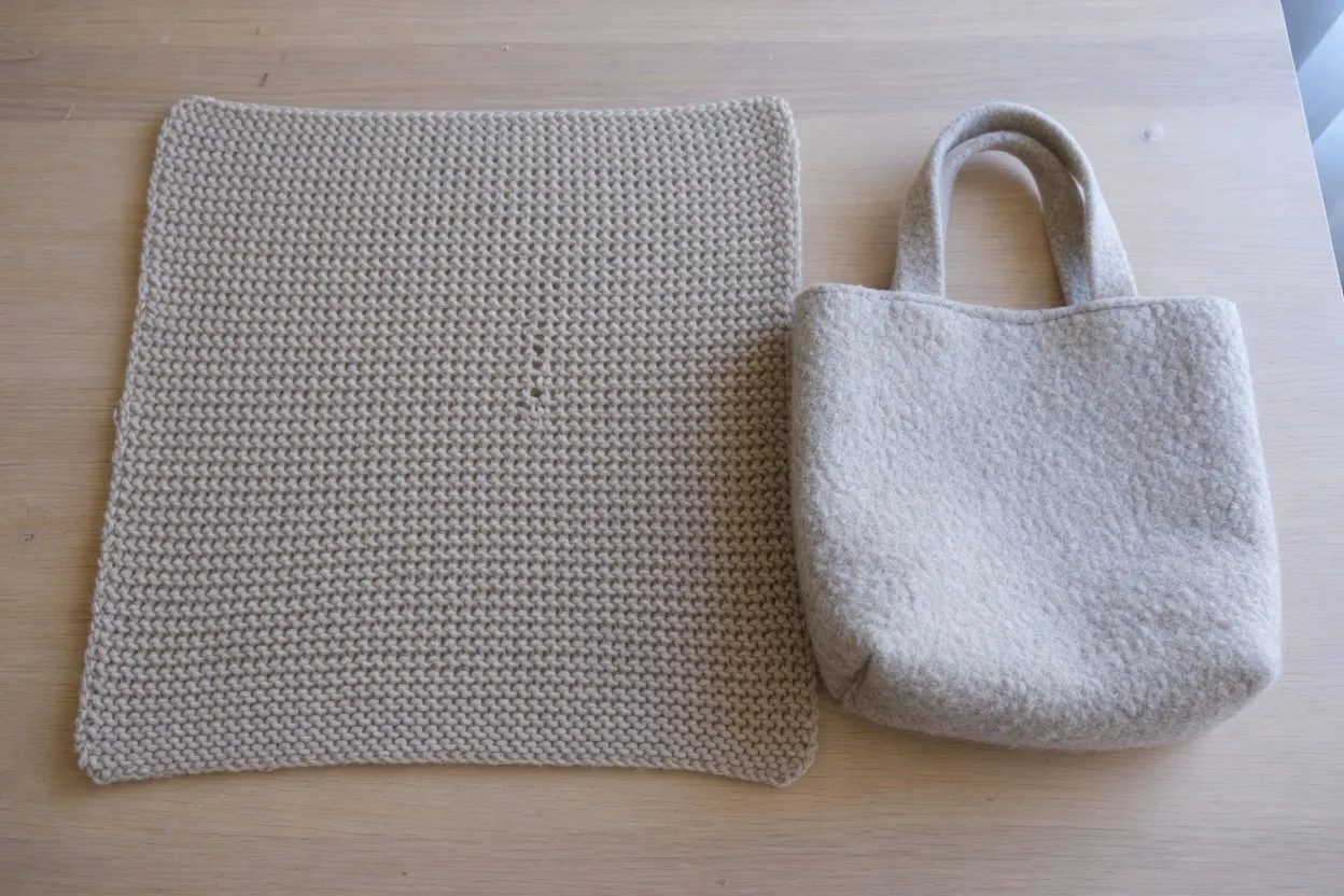 A large oatmeal knit rectangle beside a smaller dense felted tote of the same wool